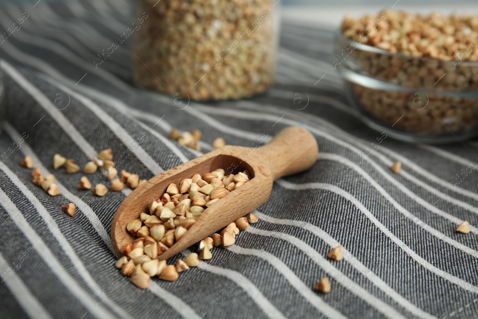 Photo of Uncooked green buckwheat grains in scoop on fabric, closeup