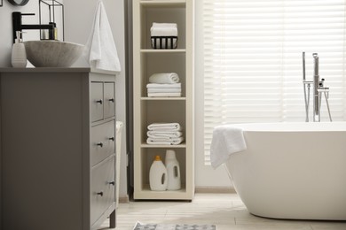 Photo of Stylish bathroom interior with grey chest of drawers and shelving unit