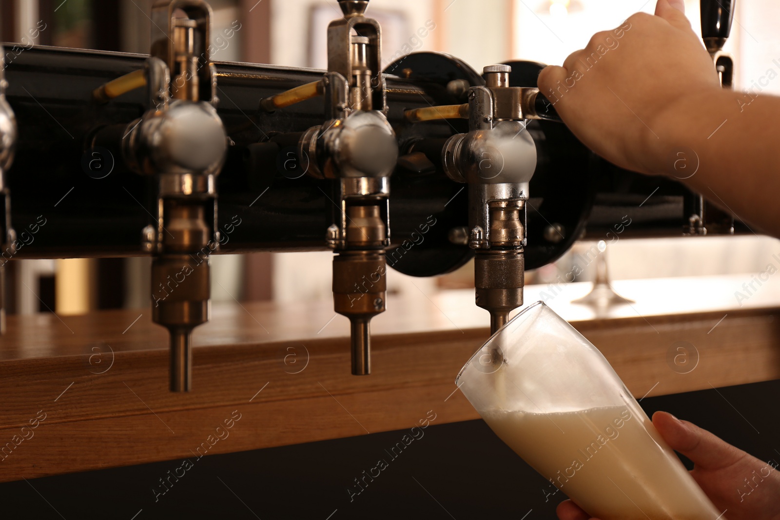 Photo of Bartender pouring fresh beer into glass in pub, closeup