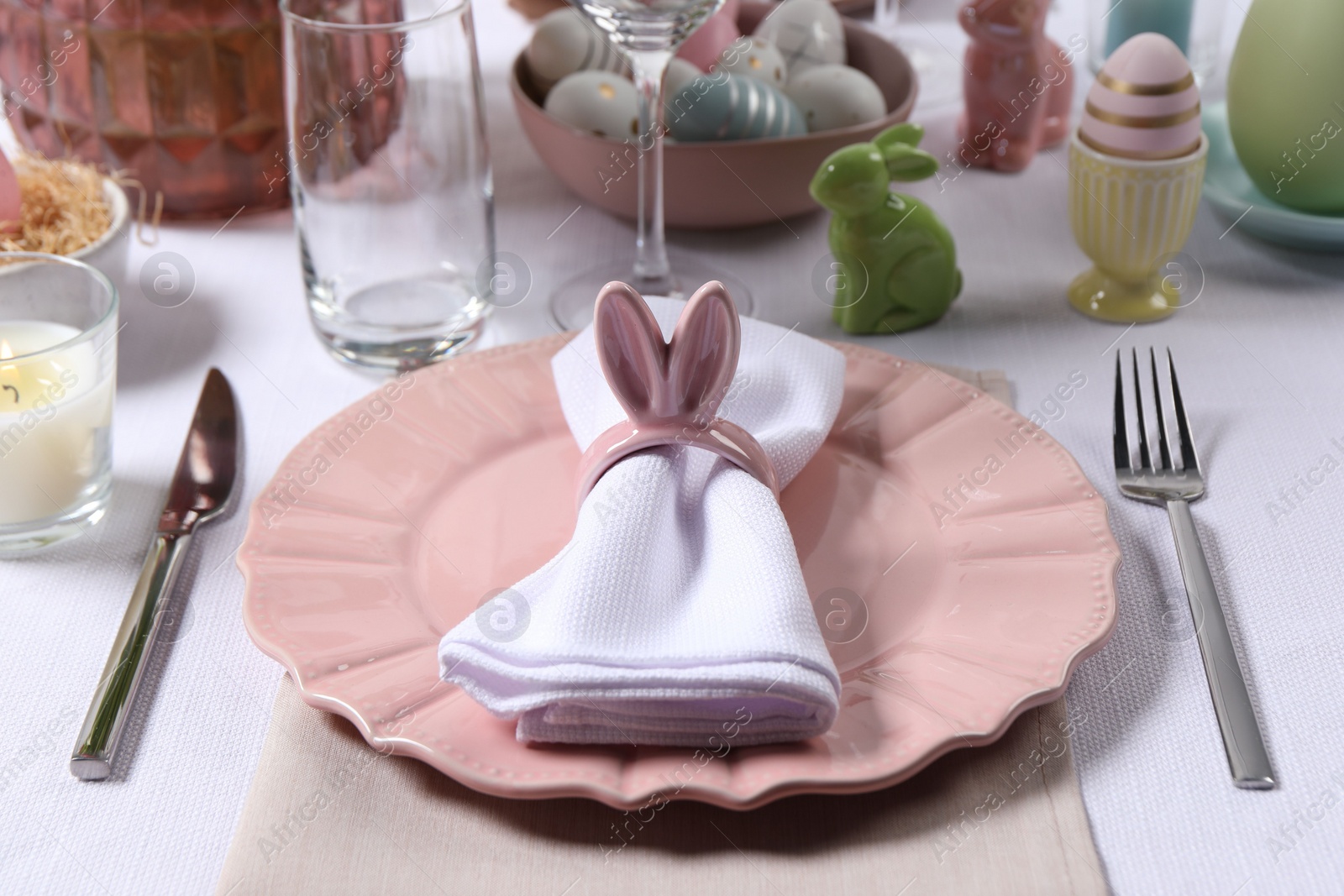 Photo of Festive table setting with napkin ring in shape of bunny ears, closeup. Easter celebration