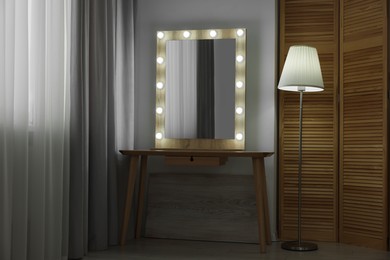 Photo of Beautiful mirror with light bulbs and lamp in makeup room