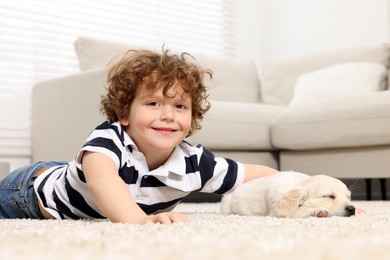 Little boy with cute puppy on beige carpet at home