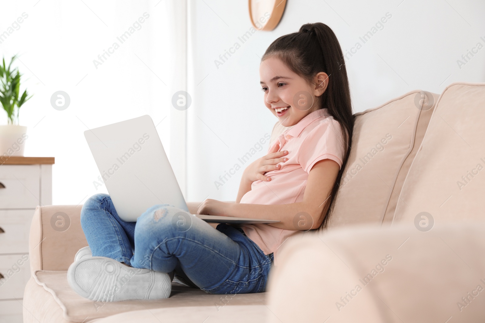 Photo of Little girl using video chat on laptop at home