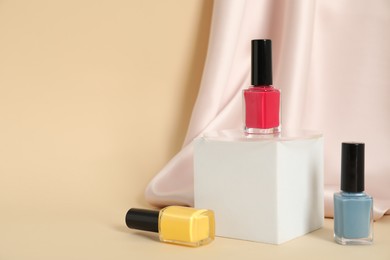 Photo of Stylish presentation of nail polishes on beige background