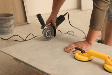Worker using saw with circular diamond blade for tile cutting indoors, closeup