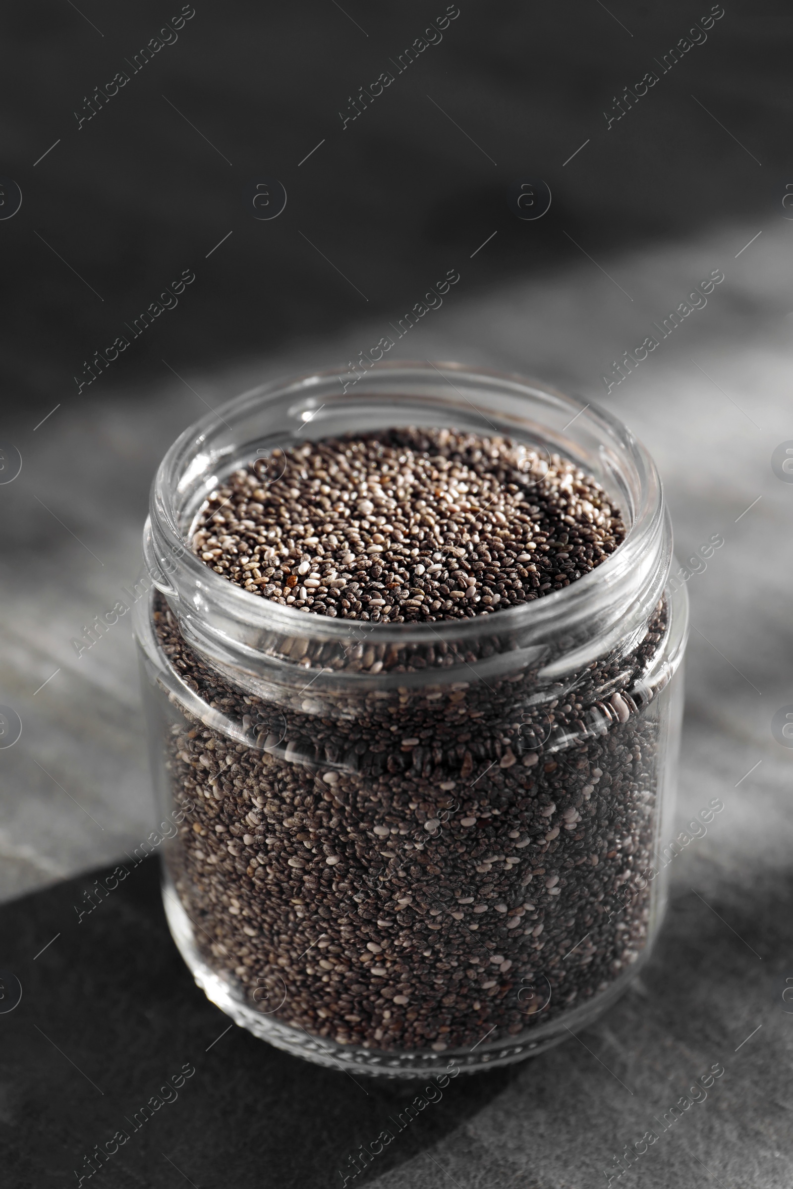 Photo of Glass jar with chia seeds on slate table