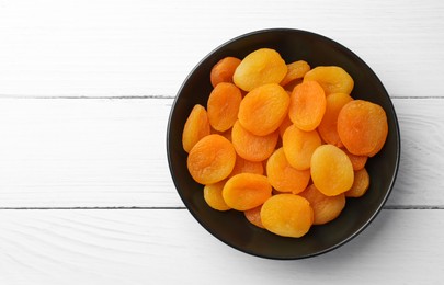 Photo of Plate of tasty apricots and space for text on white wooden table, top view. Dried fruits