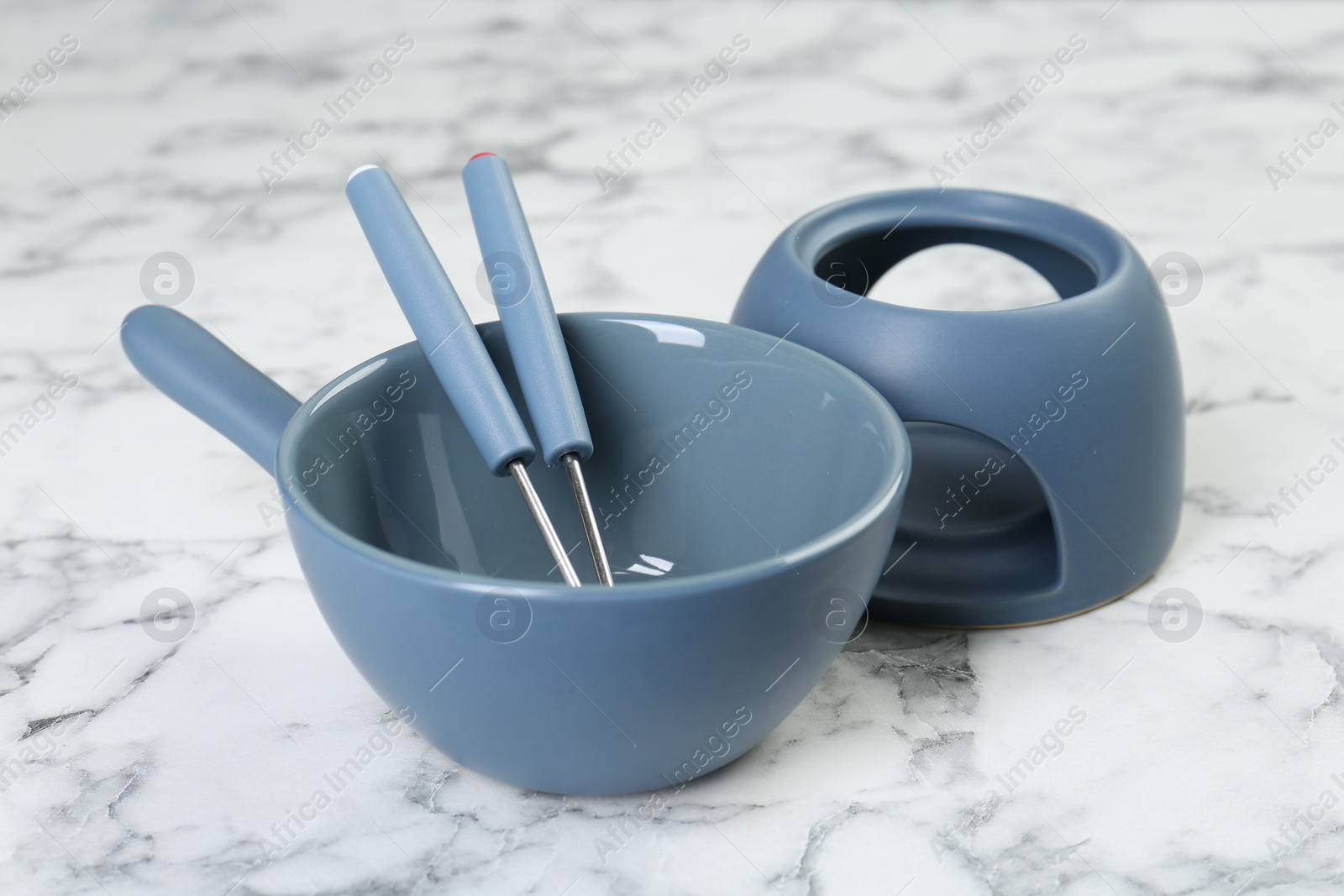 Photo of Fondue set on white marble table, closeup