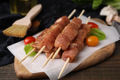 Photo of Skewers with cut raw marinated meat on wooden table