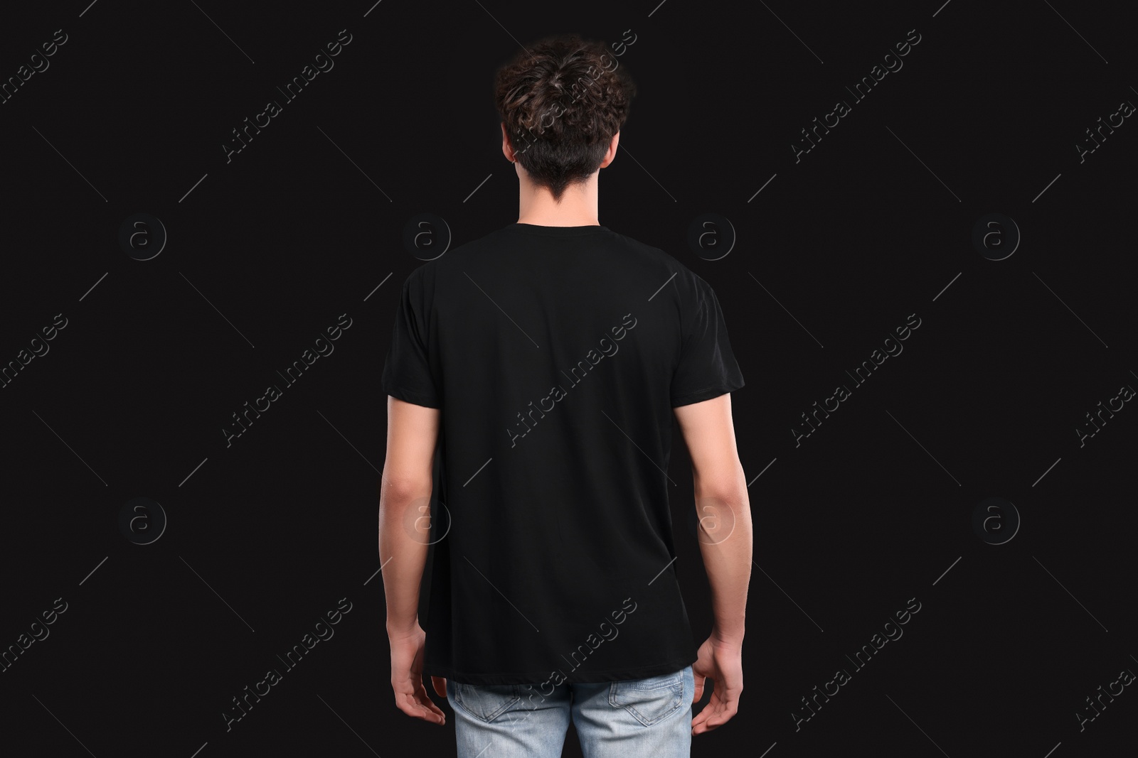 Photo of Man wearing stylish t-shirt on black background, back view. Mockup for design