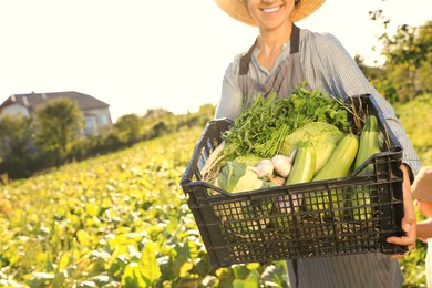 Woman with crate of different fresh ripe vegetables on farm, closeup. Space for text