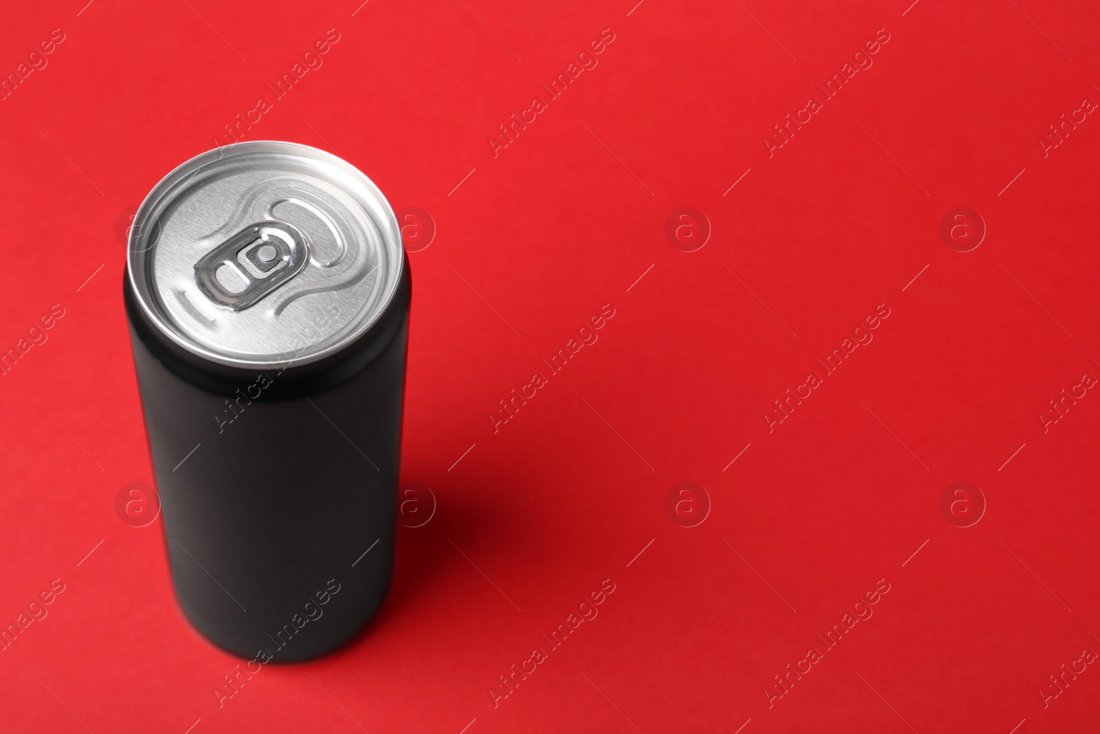 Photo of Energy drink in can on red background, space for text