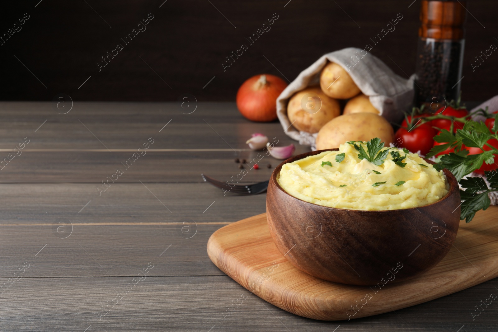 Photo of Bowl of freshly cooked mashed potatoes with parsley served on wooden table. Space for text