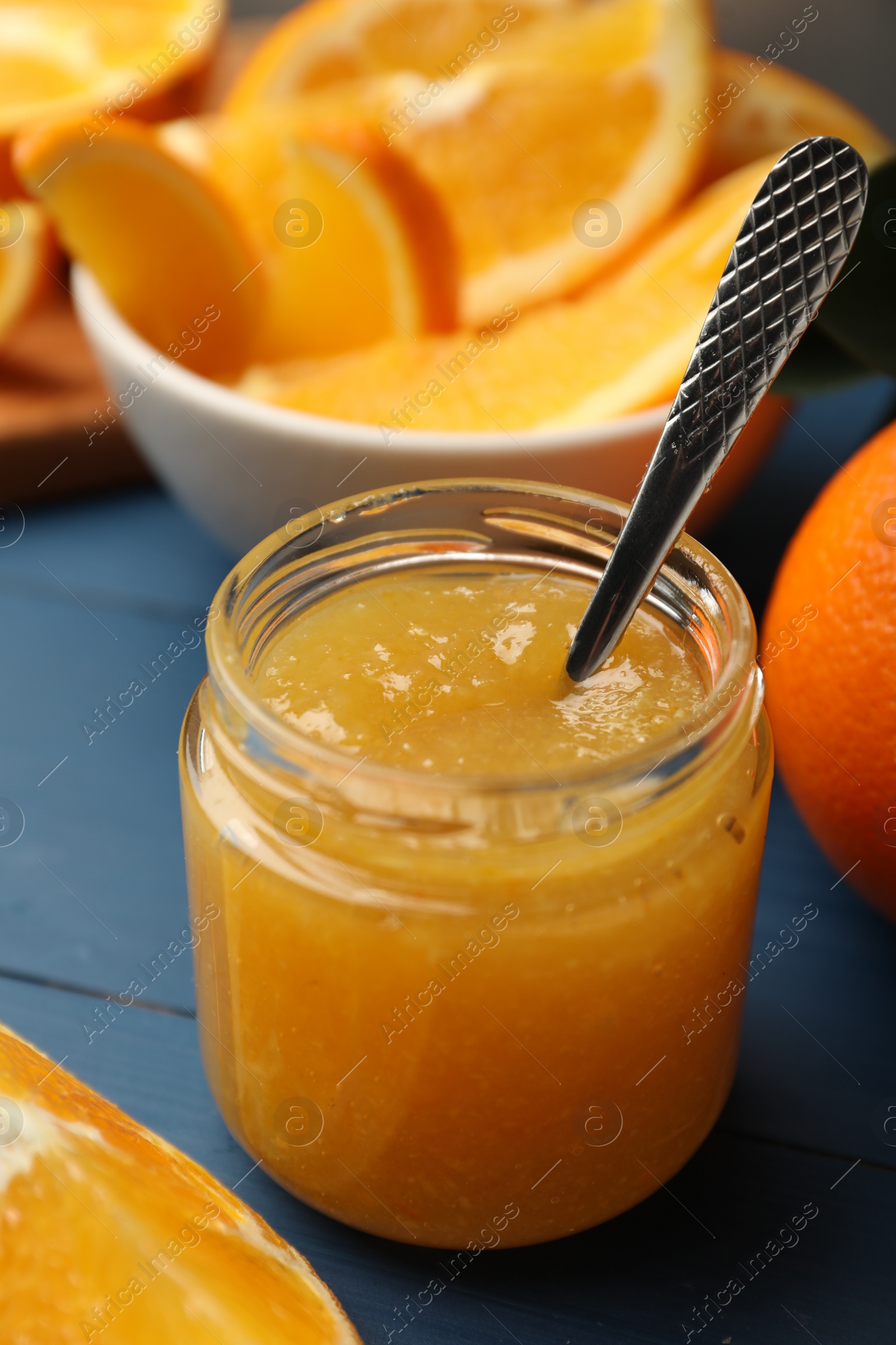 Photo of Delicious orange marmalade in jar on blue wooden table