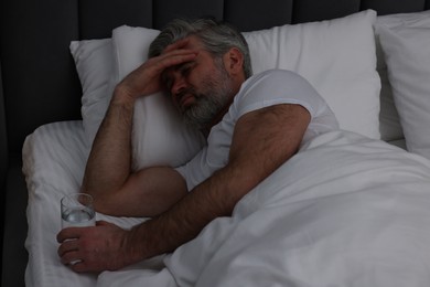 Photo of Mature man suffering from headache in bed at night