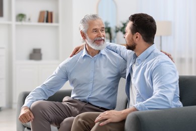 Photo of Happy son and his dad on sofa at home