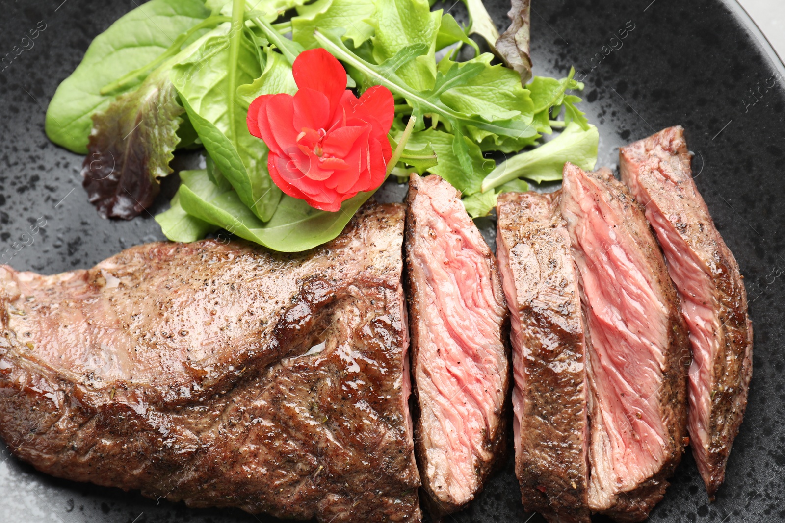 Photo of Pieces of delicious grilled beef meat and greens on plate, top view