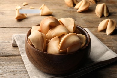 Photo of Tasty fortune cookies with prediction on wooden table, closeup