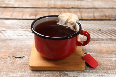 Tea bag in cup with hot drink on wooden rustic table, closeup