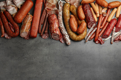 Photo of Different types of sausages on grey background, flat lay. Space for text