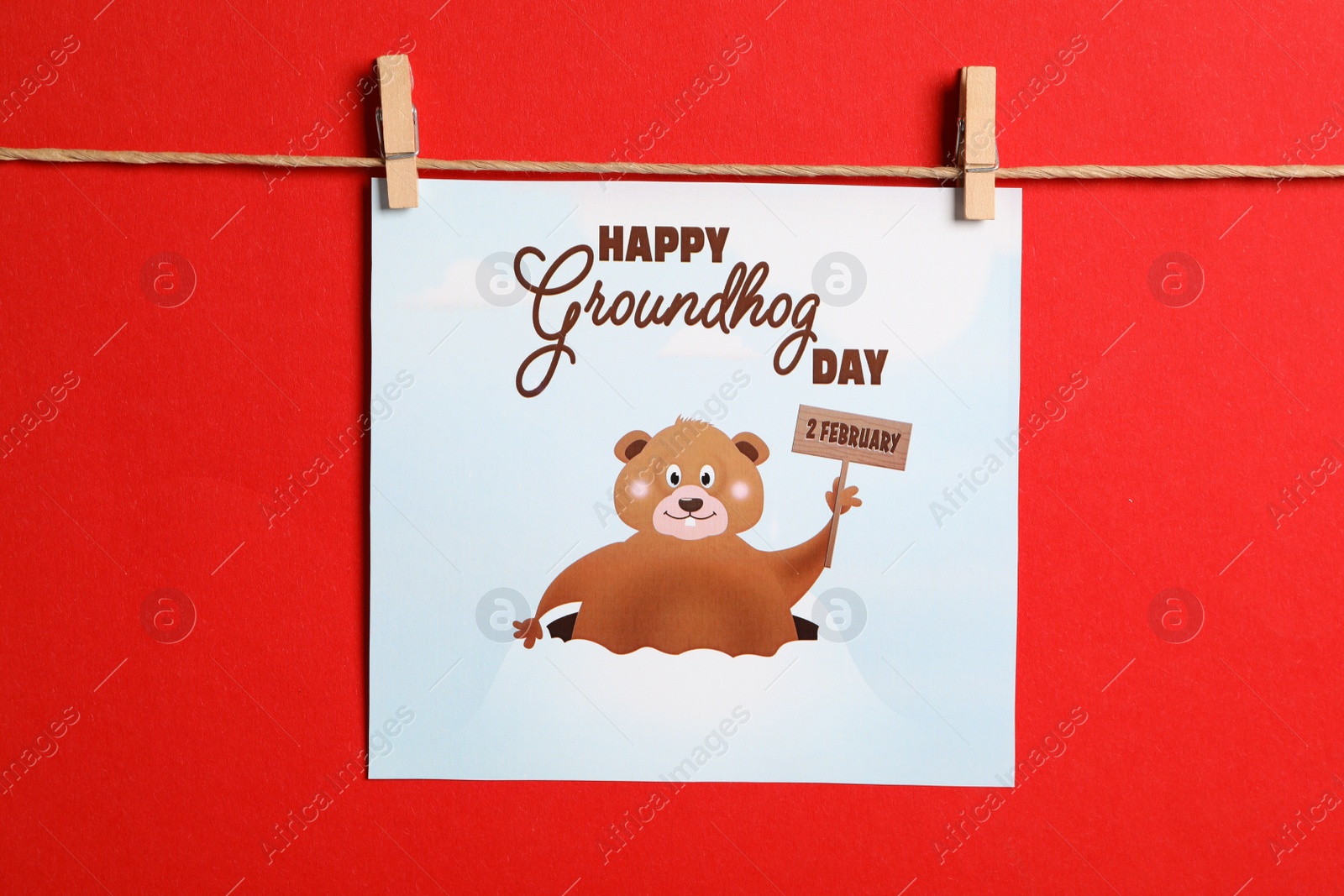 Photo of Happy Groundhog Day greeting card hanging on red background