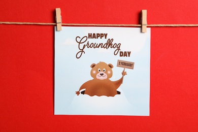 Photo of Happy Groundhog Day greeting card hanging on red background