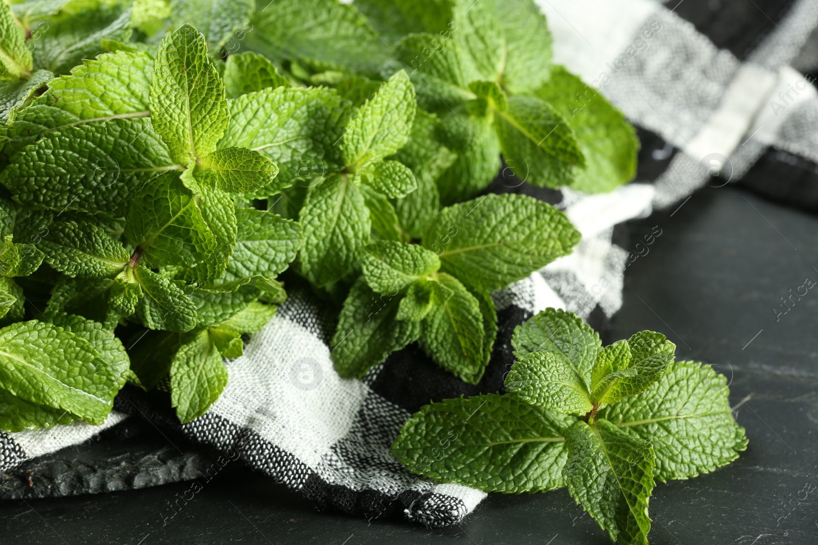 Photo of Fresh green mint leaves on black table, closeup