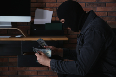 Dangerous masked criminal stealing money from house