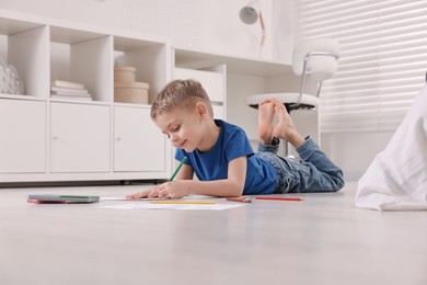 Photo of Cute little boy drawing on warm floor at home. Heating system