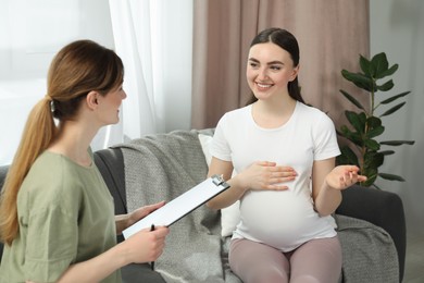 Doula working with pregnant woman on sofa at home. Preparation for child birth