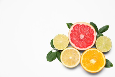 Photo of Different cut citrus fruits and leaves on white table, flat lay. Space for text