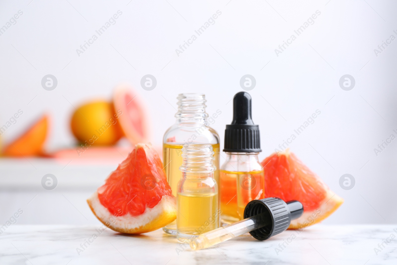 Photo of Bottles of essential oil and grapefruit slices on table