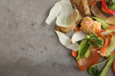 Photo of Peels of fresh vegetables on grey textured table, flat lay. Space for text
