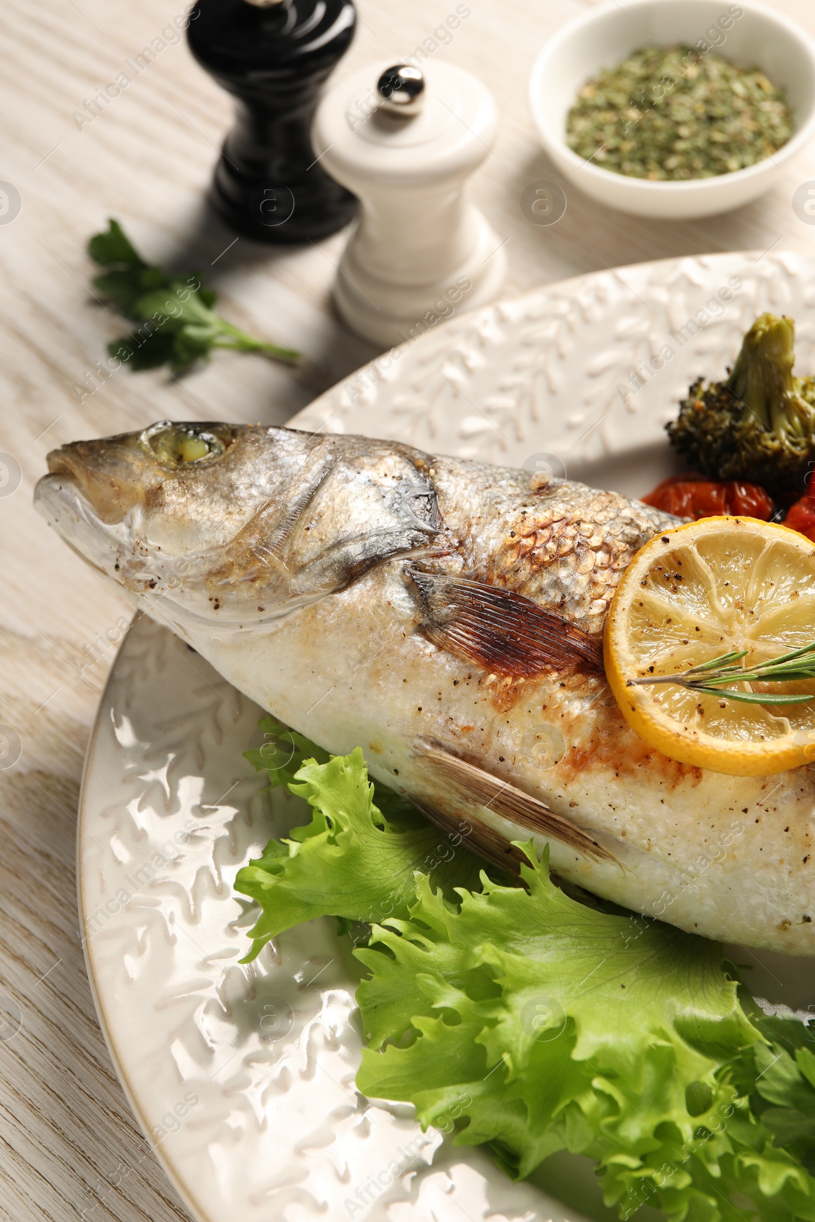 Photo of Delicious baked fish and vegetables on wooden table