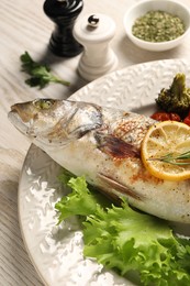 Photo of Delicious baked fish and vegetables on wooden table