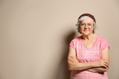 Portrait of elderly woman in hipster outfit on color background. Space for text