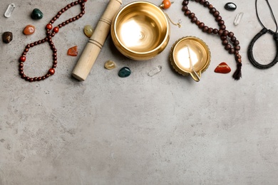Flat lay composition with golden singing bowl on grey table, space for text. Sound healing