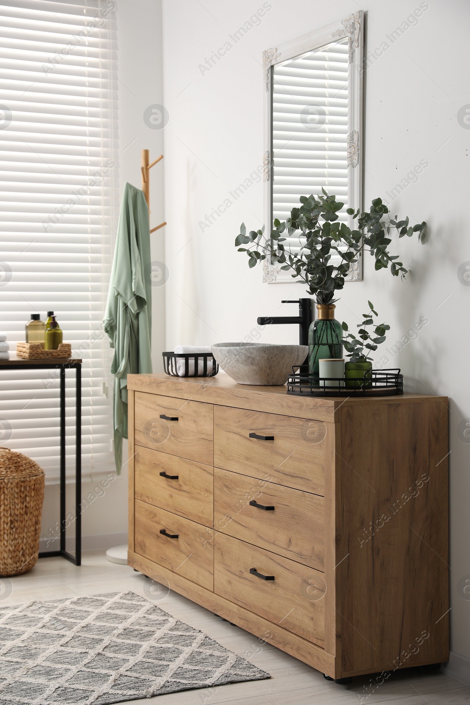 Photo of Modern bathroom interior with stylish mirror, eucalyptus branches, vessel sink and wooden vanity