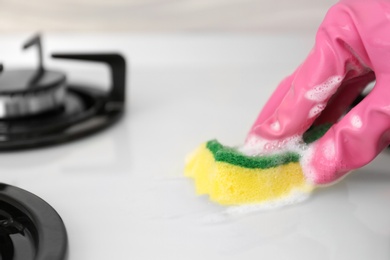 Person cleaning gas stove with sponge, closeup