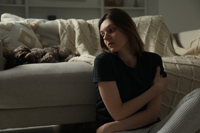 Photo of Sad young woman and her dog at home