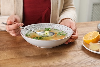 Photo of Sick woman eating fresh homemade soup to cure flu at table, closeup