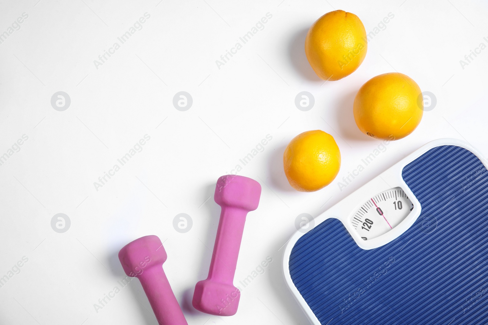 Photo of Scales, oranges and dumbbells on white background, top view