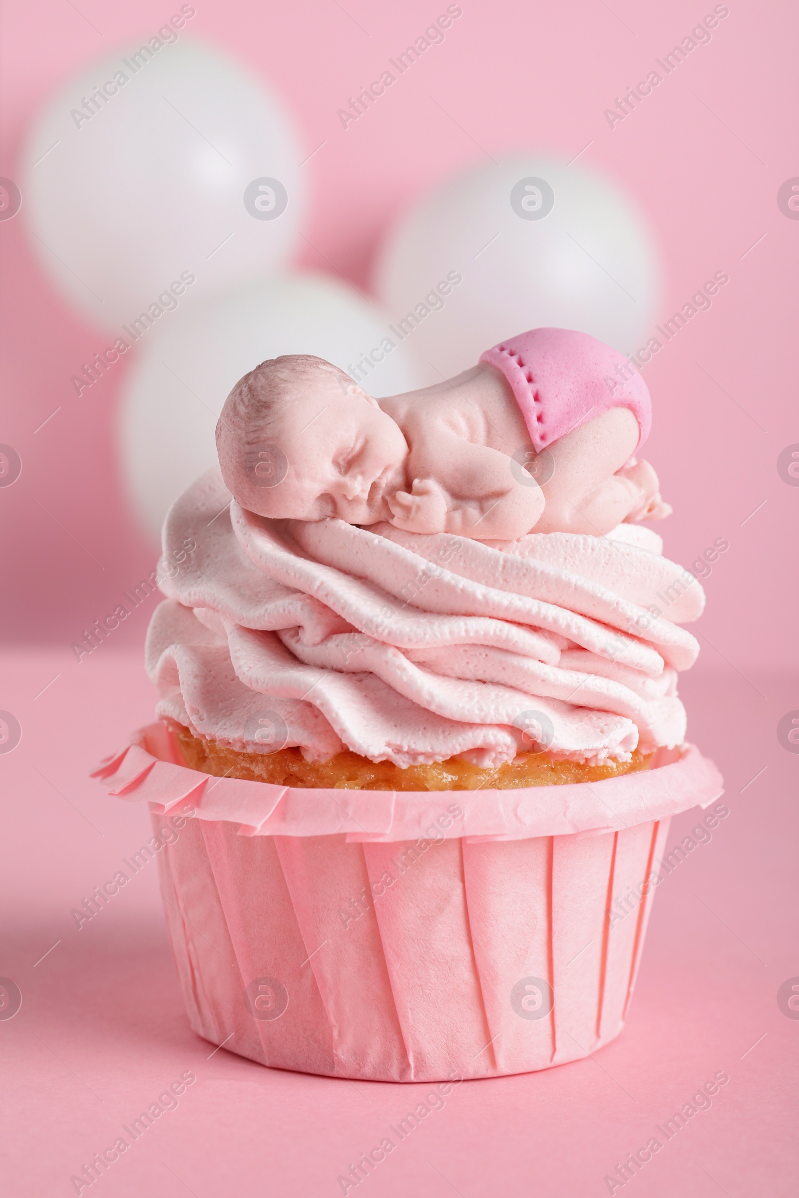 Photo of Beautifully decorated baby shower cupcake for girl with cream and topper on pink background