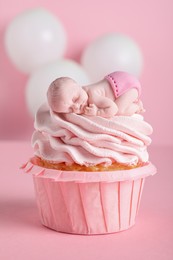 Photo of Beautifully decorated baby shower cupcake for girl with cream and topper on pink background