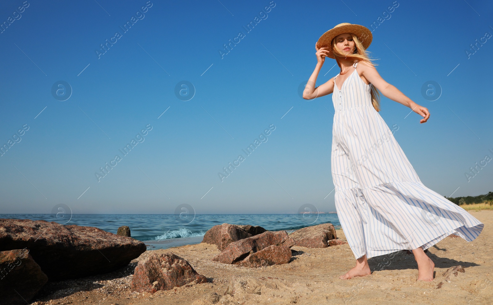 Photo of Beautiful young woman with straw hat near sea on sunny day in summer