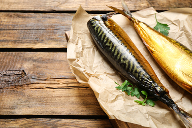 Photo of Tasty smoked fish with parsley on wooden table