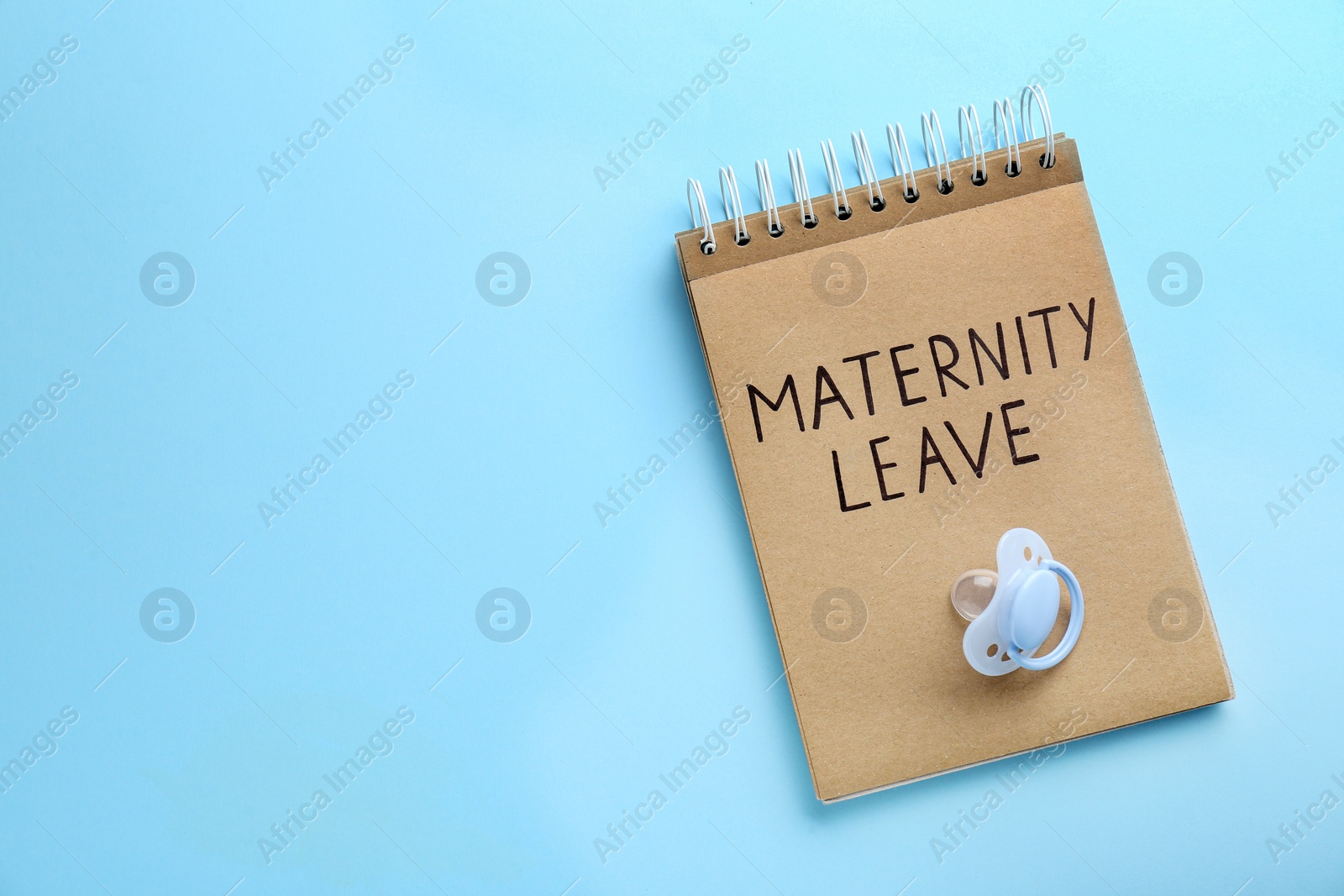 Photo of Notepad with words Maternity Leave and pacifier on light blue background, top view. Space for text