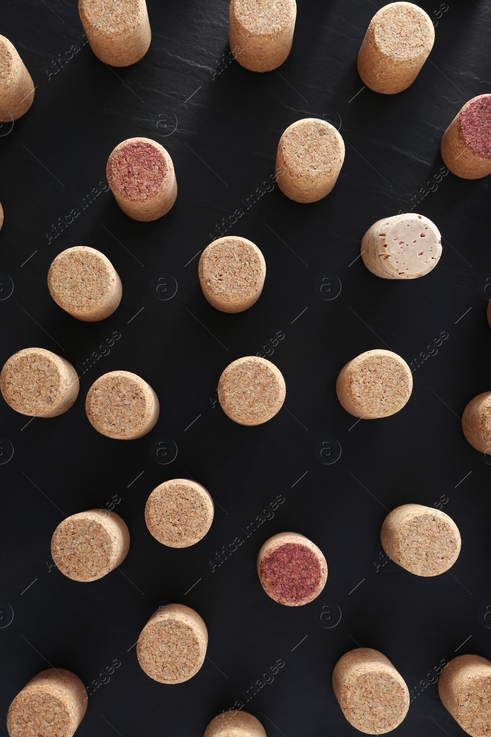 Photo of Wine bottle corks on black table, flat lay