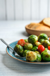 Photo of Roasted Brussels sprouts with cherry tomatoes on white wooden table