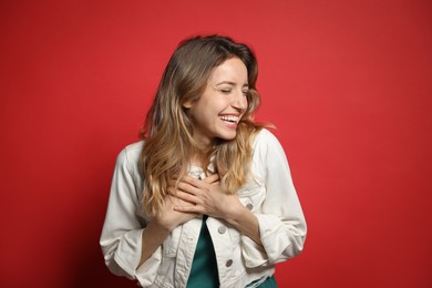 Cheerful young woman laughing on red background